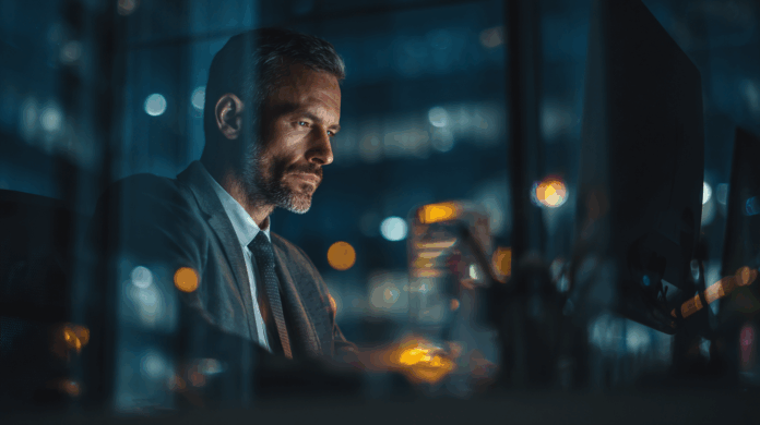 Profissional de segurança cibernética (CISOs) analisando gráficos em um escritório moderno de alta tecnologia, destacando dados e estratégias de segurança digital.