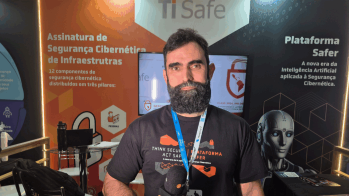 Thiago Branquinho, CTO da TI Safe, durante entrevista no estande da empresa no Mind The Sec 2025, apresentando a plataforma Safer baseada em IA para segurança cibernética de infraestruturas críticas.